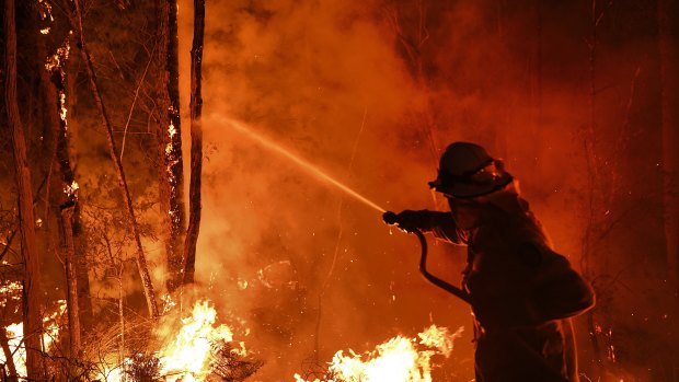 A firefighter works through the night to prevent a blaze crossing the Kings Highway between Nelligen and Batemans Bay, on the NSW South Coast, on January 2.