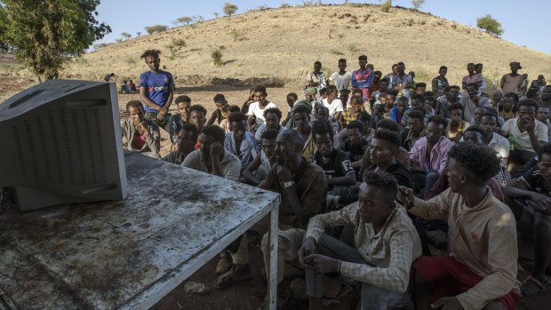 Tigranyan men who fled the conflict in Ethiopia's Tigray region, watch the news on a television, at Umm Rakouba refugee camp in Qadarif, eastern Sudan.