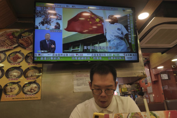 A man has lunch as the Chinese national anthem is broadcast live while a reading of a controversial anthem law takes place in the Hong Kong legislature last month.