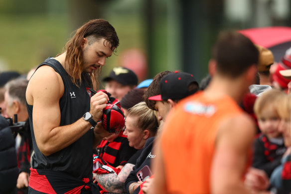 Essendon ruckman Sam Draper signs an autograph on Saturday.