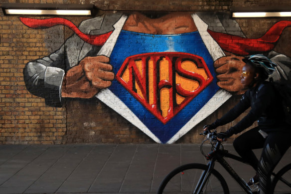 A cyclist rides past an NHS mural in London.