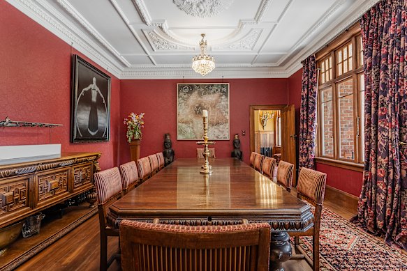 The elegant dining room with oak table,  ornate ceiling and eclectic artworks. 