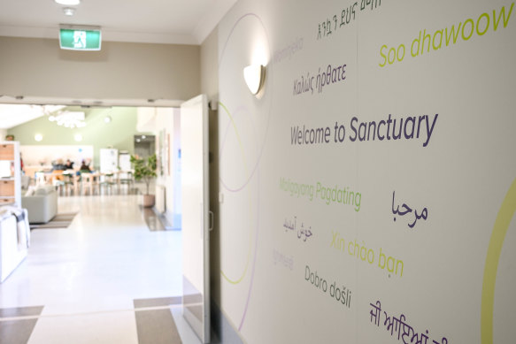 Two clients staying in the Safe Steps ‘Sanctuary’ service do an activity with case workers in a light-filled communal area.