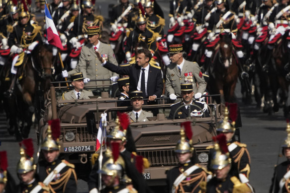 French President Emmanuel Macron waves as he stands in the command car driving down the Champs-Elysees in Paris during this year’s Bastille Day parade. 