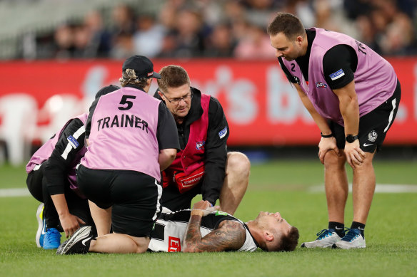 Jamie Elliott is attended by Collingwood medical staff after injuring his leg.