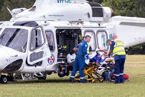 Paramedics prepare to transport a patient by helicopter after 10 people, who had gathered to farewell the Newcastle Knights team bus, were injured by a car.