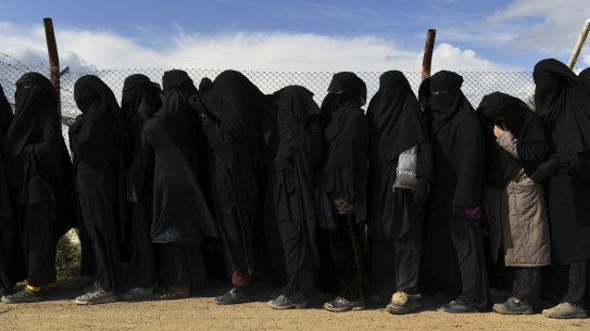 Foreign ISIS wives and children line up near the foreign section of Al Hawl camp to be taken to the shops.