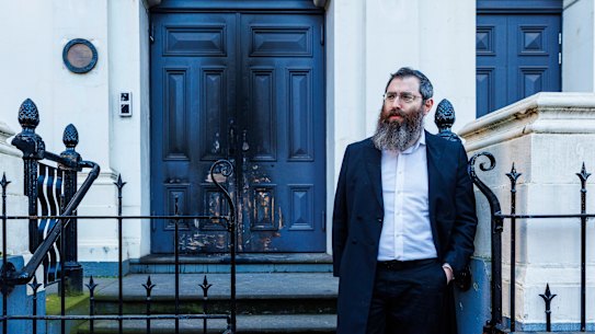 Rabbi Dovid Gutnick stands outside the charred front door of the East Melbourne synagogue on Saturday morning.