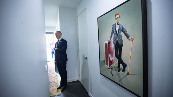 Auctioneer Jarrod Couch stands by a portrait of Rhys Nicholson before the auction.