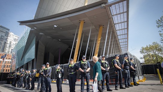 A woman walks past a police barricade outside the Melbourne Convention and Exhibition Centre on Tuesday. Thousands of protesters are expected outside on Wednesday.