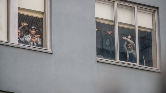Some of the refugees and asylum seekers detained at the Mantra Hotel in Preston watch a protest on the weekend from a window.