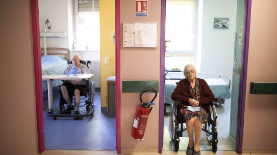 Marie Lithard, right, and her neighboor Yves Chretien sit looking out of their rooms in a nursing home in Ammerschwir, France.