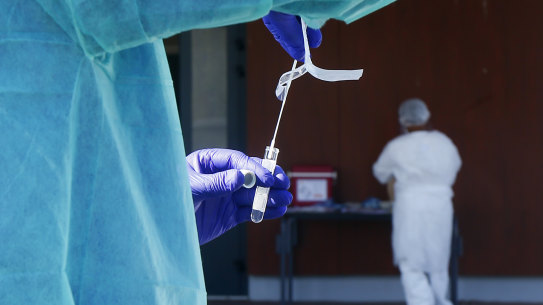 A technician holds a COVID-19 nasal swab for testing. 