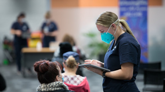 Living with COVID-19: People wait to be vaccinated.