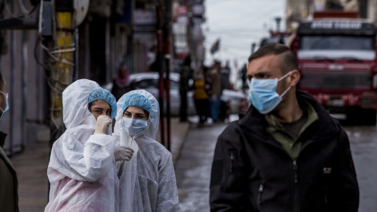 Medical workers oversee the disinfection of the streets to prevent the spread in Qamishli, Syria.