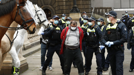 Police arrest a man for breaching the Chief Health Officer's directives at a protest in Melbourne's CBD on Sunday. 