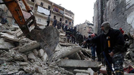 Syrian Civil Defence workers and security forces search through the wreckage of fallen buildings, in Aleppo.