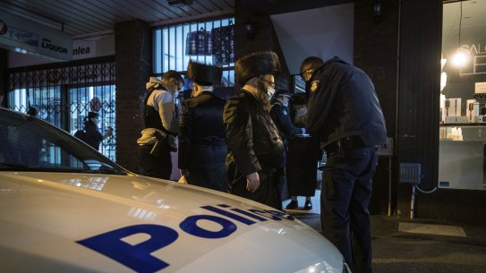 Police take the details of people outside the synagogue on Tuesday. 