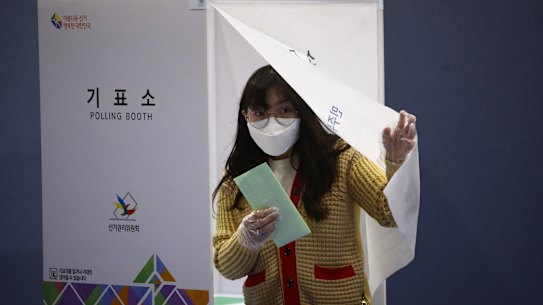 A South Korean woman wears a mask and plastic gloves cast her vote in a polling station on the Parliamentary election in Seoul.