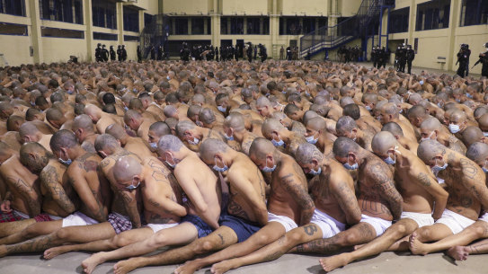 Inmates crammed into a prison's central area, wearing masks, during a security operation.