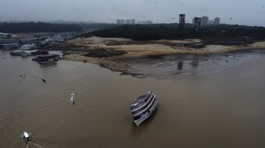 A boat is stuck in the Negro River during a drought in Manaus, Amazonas state, Brazil, on Monday. The high rises of the Manaus CBD are visible in the background.