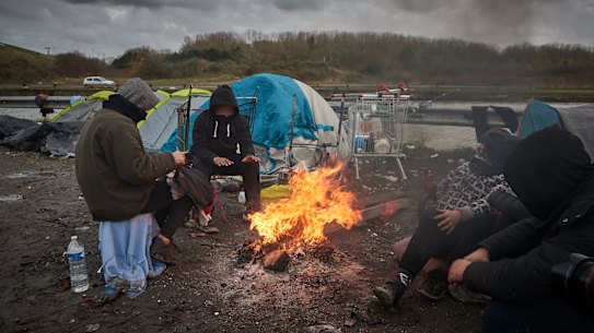 Refugees sit by a fire in Dunkirk, France, on Thursday.