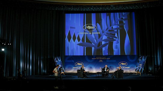 Cannes Festival director Thierry Fremaux, centre, festival president Pierre Lescure, right, and journalist Laurent Weil talk during the presentation of the festival line-up, in an empty cinema in France in 2020
