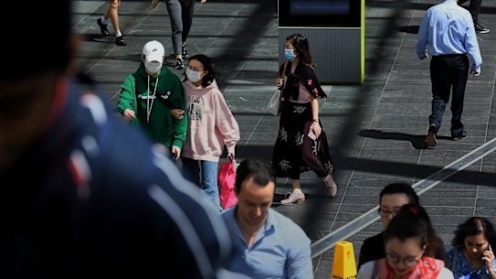 People wear a face mask walk along the street in Chatswood, Sydney. 12th March, 2020. Photo: Kate Geraghty/SMH