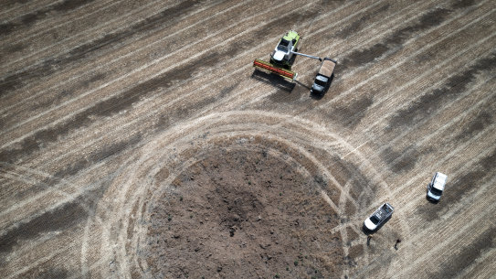 A farmer collects harvest on a field around a crater left by a Russian rocket ten kilometres from the front line in the Dnipropetrovsk region, Ukraine, on July 4, 2022.