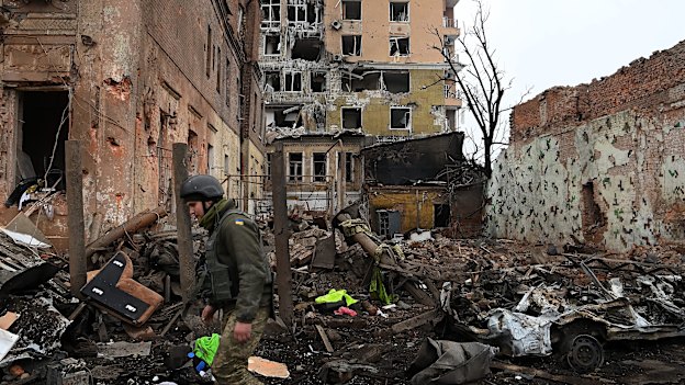 Ukrainian soldier walks past damaged buildings caused by an air strike that hit the military police building in the city centre of Kharkiv.