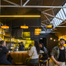 Bar Spontana’s fitout features brick walls, exposed roof trusses and colourful artwork.