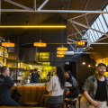 Bar Spontana’s fitout features brick walls, exposed roof trusses and colourful artwork.