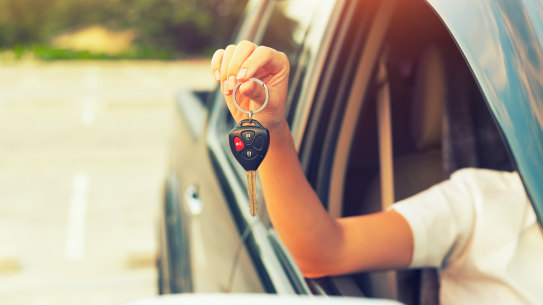 Woman’s hand holding car key. generic first car, young adult car, Millennial.