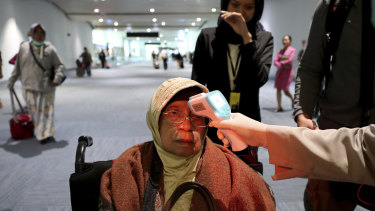 A health official scans the body temperature of a passenger as she arrives at the Soekarno-Hatta International Airport in Tangerang, Indonesia.