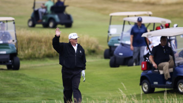 President Donald Trump waves to protesters while playing golf at the loss-making Trump Turnberry in Scotland.