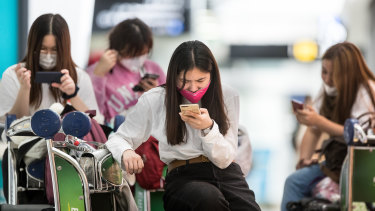 Travellers arrive at Melbourne Airport wearing face masks in January.