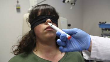 Mâna doctorului Clair Vandersteen umflă un tub de mirosuri sub nasul unei paciente legate la ochi, Gabriella Forgione, în timpul testelor efectuate într-un spital din Nisa pentru a ajuta la determinarea de ce nu a putut să mirosească sau să guste de când a contractat COVID-19.
