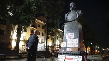 An elderly man looks at a statue of Felix Dzerzhinsky in Minsk, Belarus. Opposition supporters had pasted signs on it earlier.