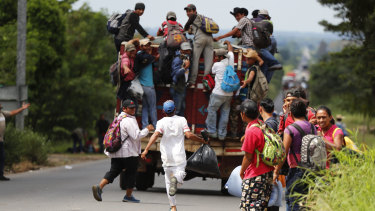 A migrant runs to catch a ride as his fellow Central American migrants, part of the caravan hoping to reach the US border, get a ride.