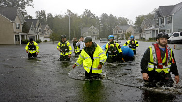 Members of the North Carolina Task Force urban search and rescue team wade through a flooded neighborhood.