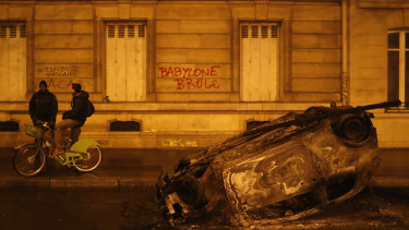 A burned out car and the slogan, "Babylon burns" in Paris on Sunday, local time.