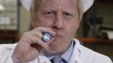 British Prime Minister Boris Johnson eats a candy stick which reads "Back Boris" during a General Election campaign trail stop at Coronation Candy on Friday.
