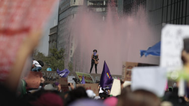 A woman stands on the ledge of a water fountain that has been stained red during a march for International Women's Day in Mexico City.