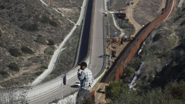 A man looks out at the US border where workers are replacing parts of the border fence with higher ones, in Tijuana, Mexico.