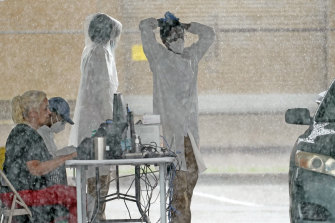 Medical workers wait under a tent as it rains at a COVID-19 testing site in Houston this week.