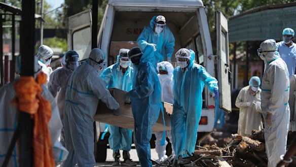 Health workers and relatives carry the body of a COVID-19 victim for cremation in Jammu, India. 
