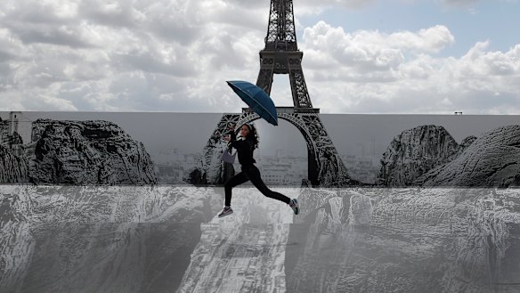 Culture in the air: a woman jumps in front of the Eiffel Tower where an exhibit has been installed. French President Emmanuel Macron is offering cash to stimulate young people’s consumption of art, music, and even video games.