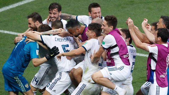National service: Russian players mob goalkeeper Igor Akinfeev after his penalty success.