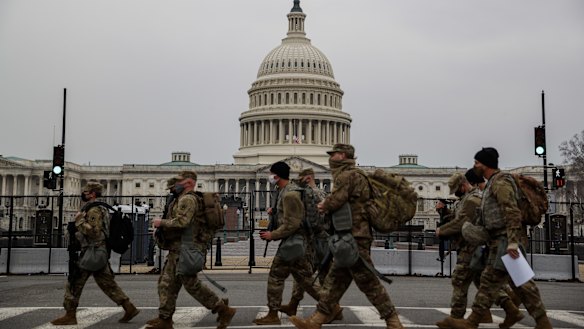 National Guard troops walk past the US Capitol building on the first day of hearings to impeach Donald Trump.