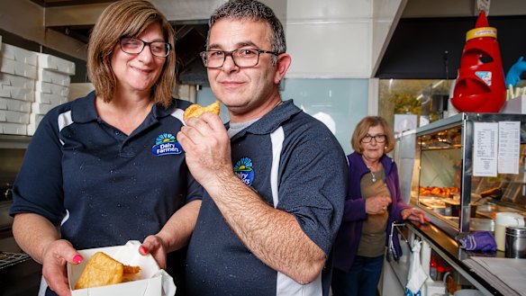Hughes Takeaway owners Nita and Peter Dorizas with their much-loved potato scallops. Peter's mum Gina (in the background) is a crucial part of  the takeaway's potato scallop process.